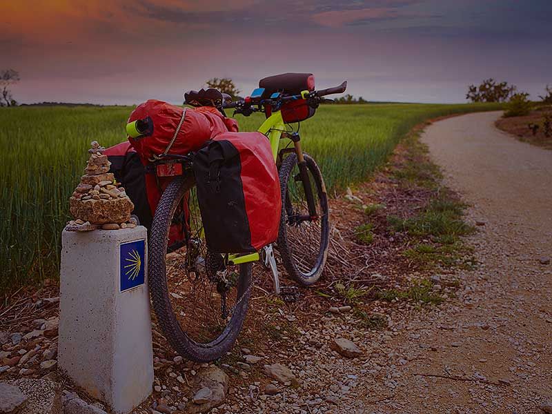 Bicicleta de cicloturismo con alforjas junto a mojón del Camino de Santiago, Navarra